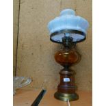 A replica wooden and brass oil lamp, converted to electricity, with an orange glass reservoir and