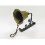 A brass wall mounted school bell, on a cast iron bracket.
