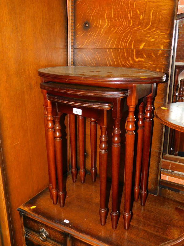 A nest of mahogany tables, with oval and green leather inserts, largest 62cm high, 56cm wide, 35cm
