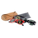 Two pairs of Ray-Ban sunglasses, with red and black frames and metal rims with tinted red lenses,