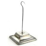 A late Victorian silver and steel desk stand, with a hook, the square base with a beaded border,