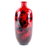 A Royal Doulton Woodcut flambe vase, decorated with deer, in dark navy, on a red ground, 27cm high.