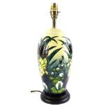 A Moorcroft pottery lamp base, decorated with rushes and lilies, on a cream ground with brass