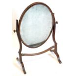 A mahogany swing frame dressing table mirror, the oval plate on shaped supports with splayed legs,