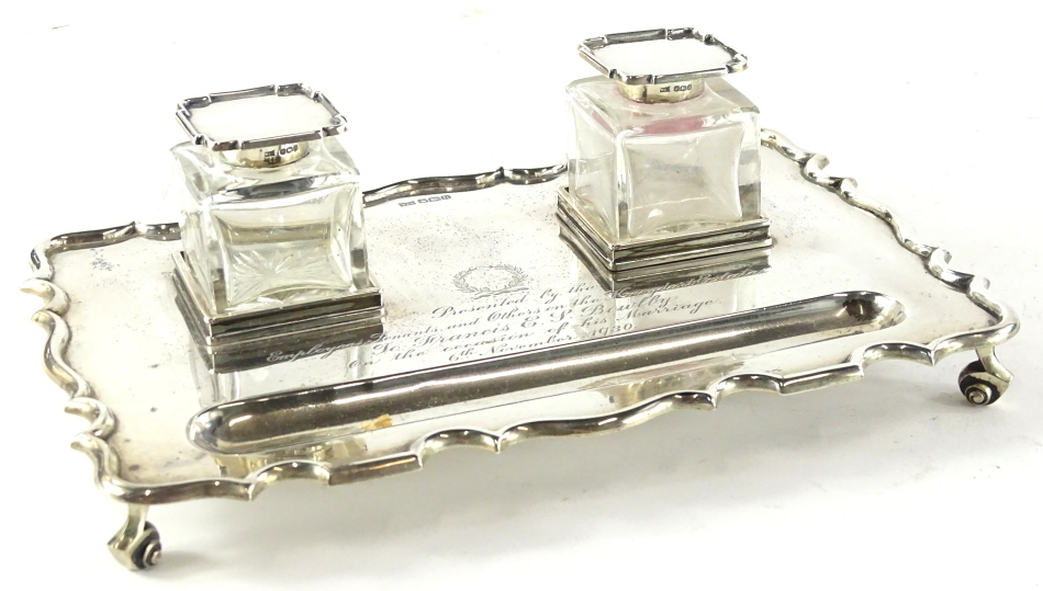 A George V silver presentation ink stand, of rectangular form with a shaped edge and two glass