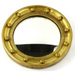 A circular gilt convex wall mirror, decorated with spheres, 35cm wide.