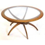 A 1960's G Plan teak coffee table, the circular moulded top with a glass insert, on a spider's leg