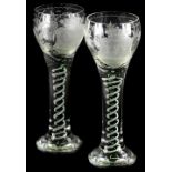 A pair of large glass goblets, each engraved with a crest and with an opaque and green twist stem,