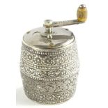 A continental part white metal pepper grinder, of barrel form, embossed with scrolls, flowers, etc.,