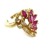 A modern dress ring, with floral type spray centre, set with oval cut rubies and round brilliant cut