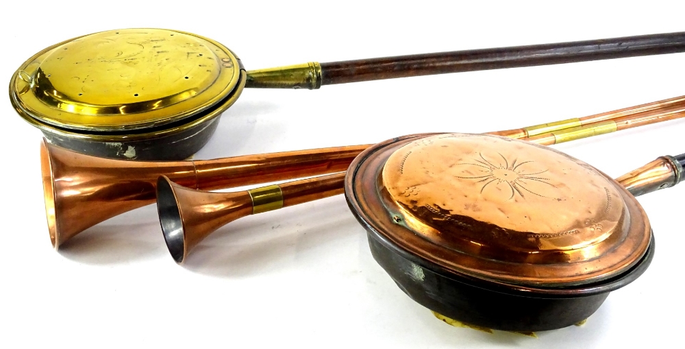 Two copper and brass hunting horns, a copper warming pan and a brass warming pan, each with a turned