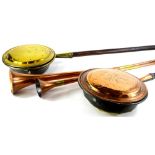 Two copper and brass hunting horns, a copper warming pan and a brass warming pan, each with a turned