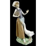 A Lladro porcelain figure of a young girl feeding a goose, numbered to underside 1052, 23cm high (