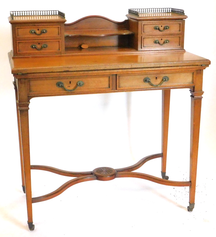 An Edwardian mahogany writing table, the raised back with two brass pierced galleries, two pairs