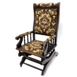 A walnut rocking chair, with a padded back, arm rests and seat, upholstered in brown and gold