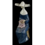 A Lladro porcelain figure of a seated nun doing embroidery, numbered to underside 5501, 20.5cm
