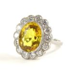 A yellow sapphire and diamond daisy ring, with central oval cut yellow sapphire 11.8mm x 8.8mm x 4.