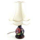 A Moorcroft pottery baluster shaped lamp base, decorated with poppies, on a navy blue ground, with