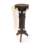 An Indian hardwood plant stand, carved overall with flowers, leaves, etc., the hexagonal top with an