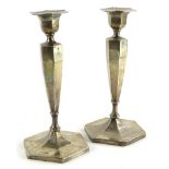 A pair of George V silver hexagonal shaped candlesticks, each with a tapering column and a domed