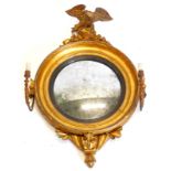 A Regency gilt gesso convex girandole wall mirror, with an eagle crest, the circular frame with an