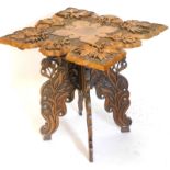 An Indian hardwood occasional table, the square shaped top carved with leaves, flowers, etc., on a