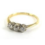 A three stone diamond dress ring, set with three tiny old cut diamonds, on a thin yellow metal band,