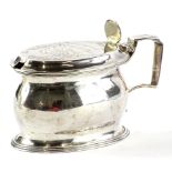 A George III oval silver mustard pot, the hinged lid with a fan shaped thumb piece, with an