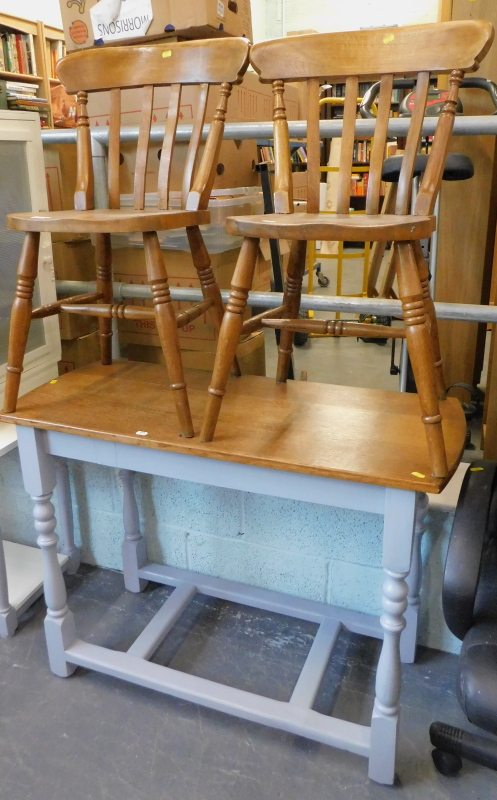 A pair of oak kitchen chairs and a narrow topped side table.