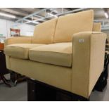 A modern cream two seater sofa.