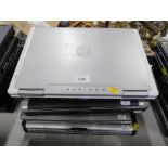 Six Dell laptops, lacking internal components and power leads.