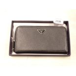 A black ladies purse, with plaque to the exterior bearing the name Prada, boxed.