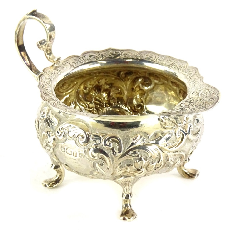 A George V silver cream boat by Walker & Hall, of compressed circular form, repousse decorated