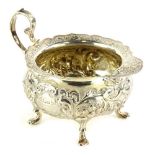 A George V silver cream boat by Walker & Hall, of compressed circular form, repousse decorated