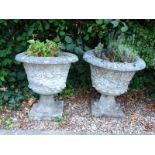 A pair of composition garden urns, each with a dragooned edge, floral and leaf sides and square