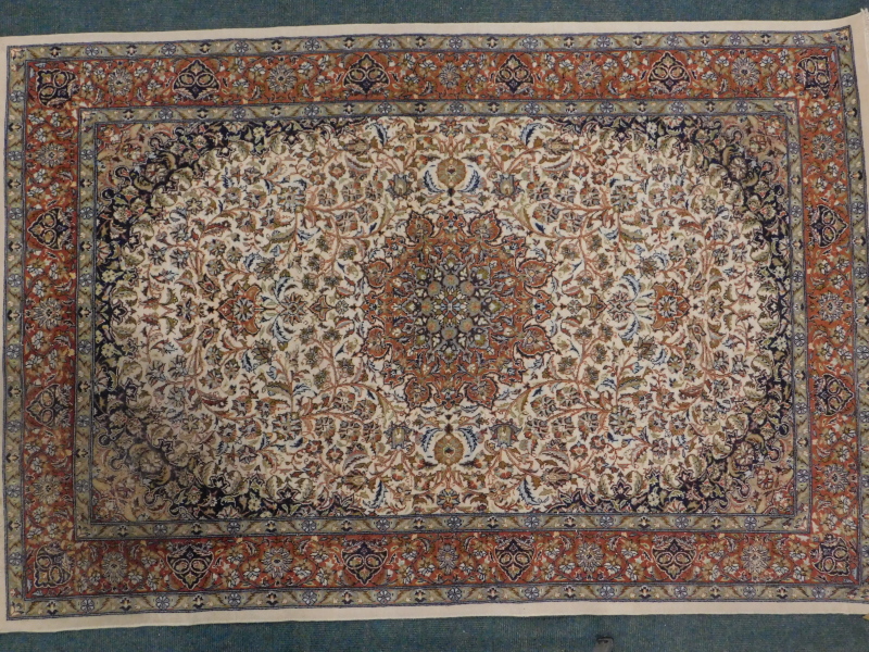 A Persian rug, with a central medallion, in orange, on a floral and leaf cream ground, with