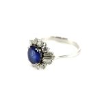 An 18ct white gold sapphire and diamond cluster ring, with oval cut dark blue sapphire, 7.4mm x 6.