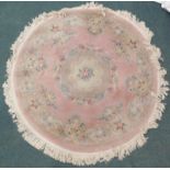 A Chinese circular cut wool carpet, decorated with flowers, scrolls, leaves, etc., on a pink
