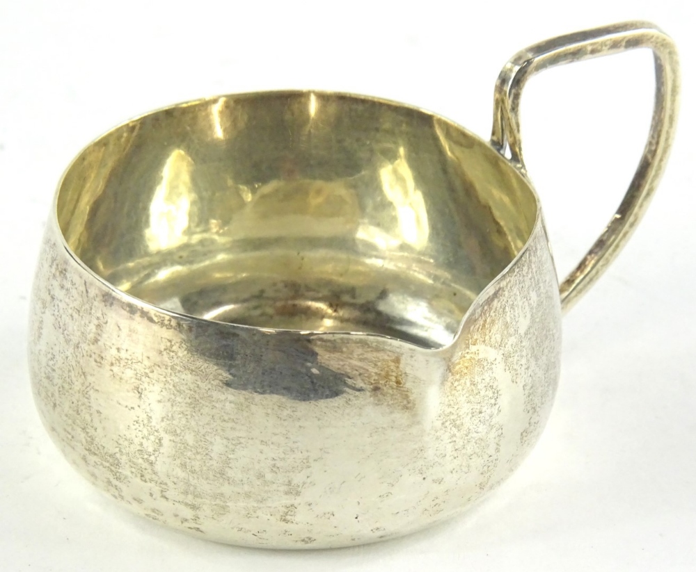 An Edwardian Arts & Crafts silver side handled milk jug, of plain form, with angular handle, Chester