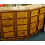 A hardwood corner bar, mounted with various wine case labels, 183cm wide.