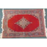 A Turkish style rug, with a central lozenge shaped medallion, on a deep red ground, with coloured