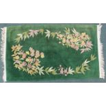A Chinese style rug, with a design of flowers and leaves, on a green ground, with tasselled ends,