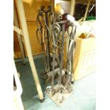 Two sets of wrought iron fire irons, with stands.