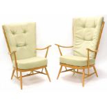 A pair of Ercol type cottage winged armchairs, with pale beech frames on turned tapering legs. The