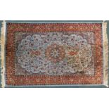 A Persian style rug, with a central medallion in orange, on a pale blue leaf and floral ground