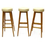 A set of three eastern hardwood bar stools, each with cream leatherette padded seat 82cm high. The