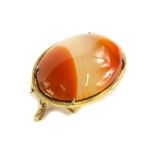 A gold framed agate set pendant/ brooch, the oval orange and white set agate in a yellow metal