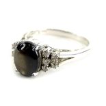 A dress ring, set with opalescent style oval black stone, with tiered white stone set shoulders,
