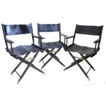 A set of three stained beech and black leather director type chairs, each with a folding base.