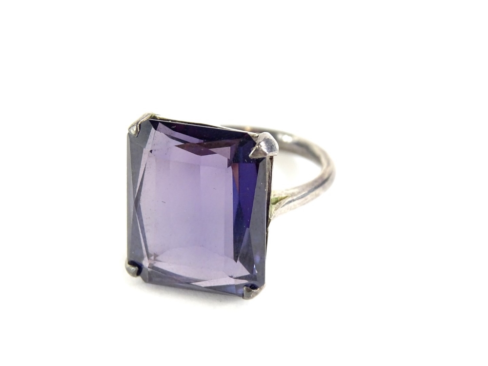 A chunky design dress ring, set with rectangular cut purple coloured paste stone, in a white metal